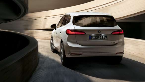 Динамічний дизайн задньої частини BMW 2 серії Active Tourer U06 2021 BMW 2 серії Active Tourer U06 2021 у кольорі Mineral White металік, вид ззаду на спіральну рампу на автостоянці