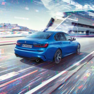 BMW 3 серії Седан, боковий задній знімок. Вид ззаду седана BMW 3 серії в день перед міською обстановкою з поворотом в три чверті.
