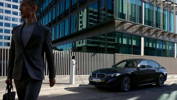 Плагін-гібрид BMW 3 серії Sedan G20, вид збоку з поворотом у три чверті на зарядці Плагін-гібрид BMW 3 серії Sedan G20, вид збоку з поворотом у три чверті на зарядці з моделлю