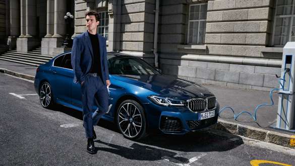 Плагін-гібрид BMW 5 серії Седан 2021 G30, вид спереду на три чверті на зарядці Плагін-гібрид BMW 5 серії Седан 2021 G30, вид спереду на три чверті на зарядці з моделлю