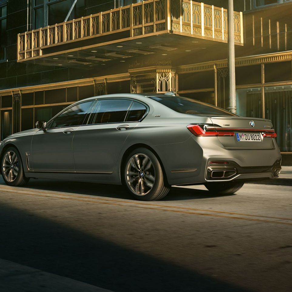 BMW M760Li xDrive з двигуном V12 BMW M760Li xDrive: вид ззаду збоку на тлі міських хмарочосів