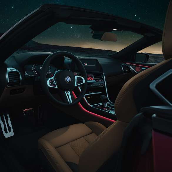 BMW M8 Competition Кабріолет, кабіна. BMW M8 Competition Кабріолет, кабіна вночі з шкіряним рульовим колесом M і червоним фоновим освітленням.
