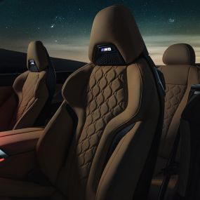 Спортивні сидіння в шкірі 'Merino'. BMW M8 Competition Кабріолет з відкритим м'яким дахом під зоряним небом, салон зі спортивними сидіннями M зі шкіри 'Merino' і червоним фоновим освітленням.