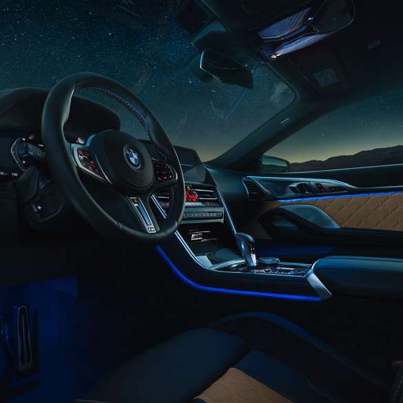 BMW M8 Competition Coupé, кабіна. BMW M8 Competition Coupé, кабіна вночі з шкіряним рульовим колесом M і синім фоновим освітленням.