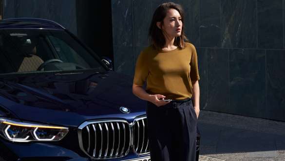 Жінка стоїть перед BMW iX BMW Roadside Assistance жінка перед BMW