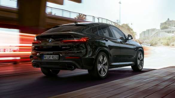 BMW X4 M40i та BMW X4 M40d, вид ззаду з поворотом в три чверті. BMW X4 M40i та BMW X4 M40d в Black Sapphire металік, за кермом, екстер'єр, вид ззаду з поворотом в три чверті зі світловими смужками.