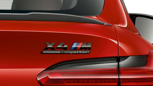 BMW X4 M Competition, задня частина з написом “X4 M Competition”. BMW X4 M Competition в Toronto Red металік, екстер'єр, вид ззаду крупним планом із заднім спойлером з карбону і позначенням «X4 M Competition».