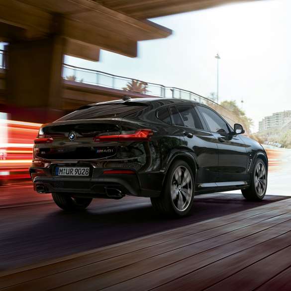 BMW X4 M40i, вид спереду з поворотом в три чверті. BMW X4 M40i в Black Sapphire металік, за кермом, екстер'єр, вид спереду з поворотом в три чверті зі світловими смужками.
