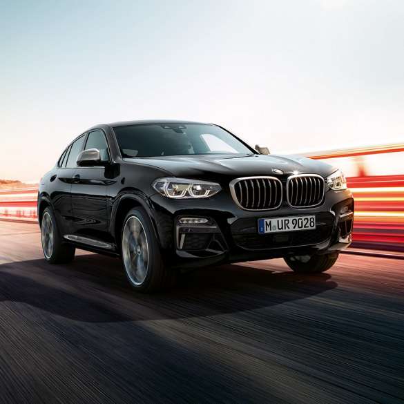 BMW X4 M40i, вид ззаду з поворотом в три чверті. BMW X4 M40i в Black Sapphire металік, за кермом, екстер'єр, вид ззаду з поворотом в три чверті зі світловими смужками.
