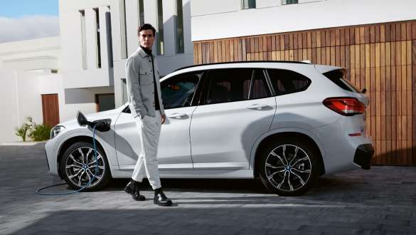 Плагін-гібрид BMW X1 xDrive25e F48 LCI, вид збоку на зарядці Плагін-гібрид BMW X1 xDrive25e F48 LCI, вид збоку на зарядці поруч із моделлю