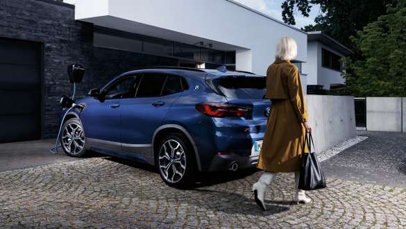 Плагін-гібрид BMW X2 xDrive25e F39, вид на машину ззаду на три чверті під час заряджання Плагін-гібрид BMW X2 xDrive25e F39, вид на машину ззаду на три чверті під час заряджання з моделлю