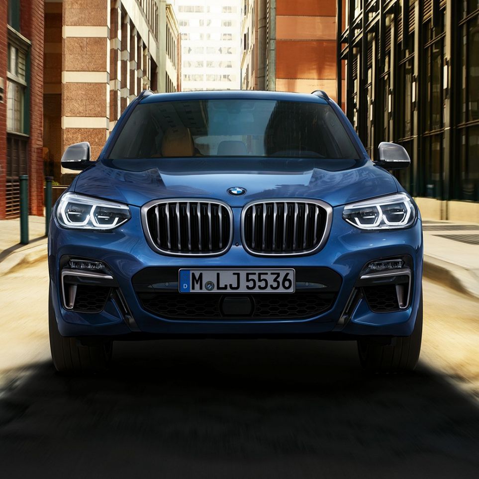 BMW X3 M40i, передній знімок перед міським пейзажем BMW X3 M40i, передній знімок перед міським пейзажем