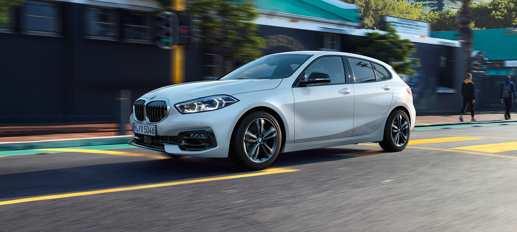 BMW 1 серії модель Sport Line, вид збоку з поворотом в три чверті. BMW 1 серії модель Sport Line в Mineral White металік, вид збоку з поворотом в три чверті, за кермом.