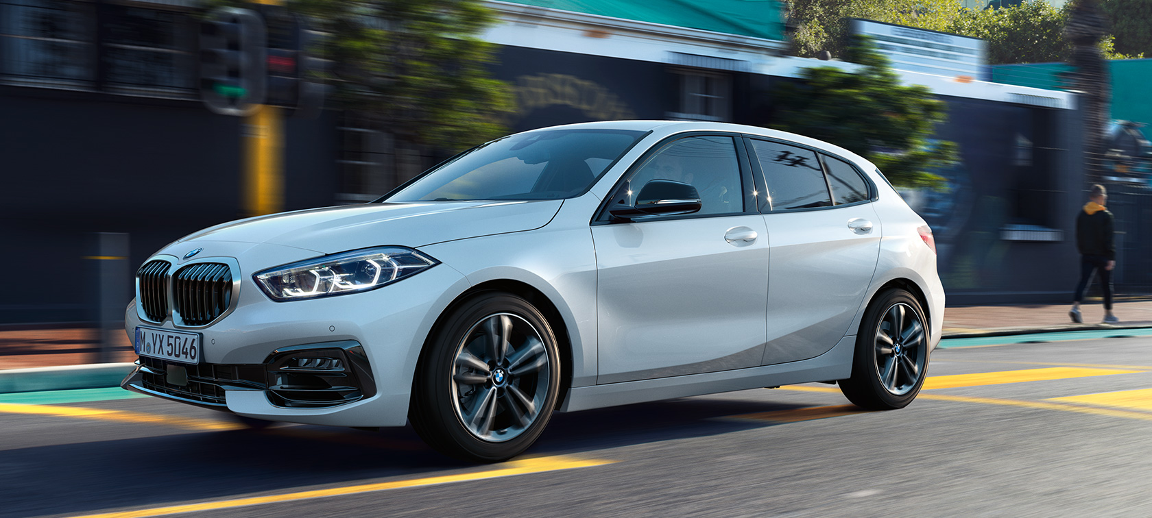 BMW 1 серії F40 модель Sport Line, вид збоку з поворотом у три чверті BMW 1 серії F40 модель Sport Line у кольорі Mineral White metallic, вид збоку з поворотом у три чверті у русі