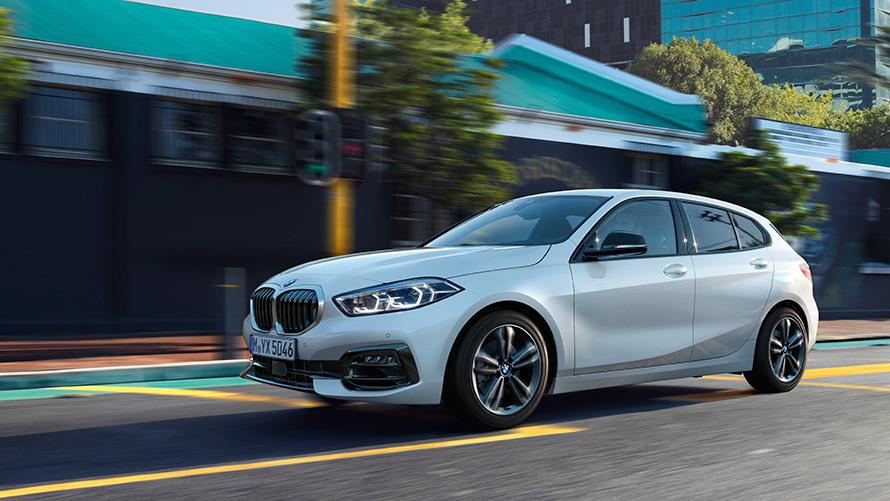 BMW 1 серії (F40) Вид збоку три чверті рухається на тлі міста BMW 1 серії (F40) Вид збоку три чверті рухається на тлі міста