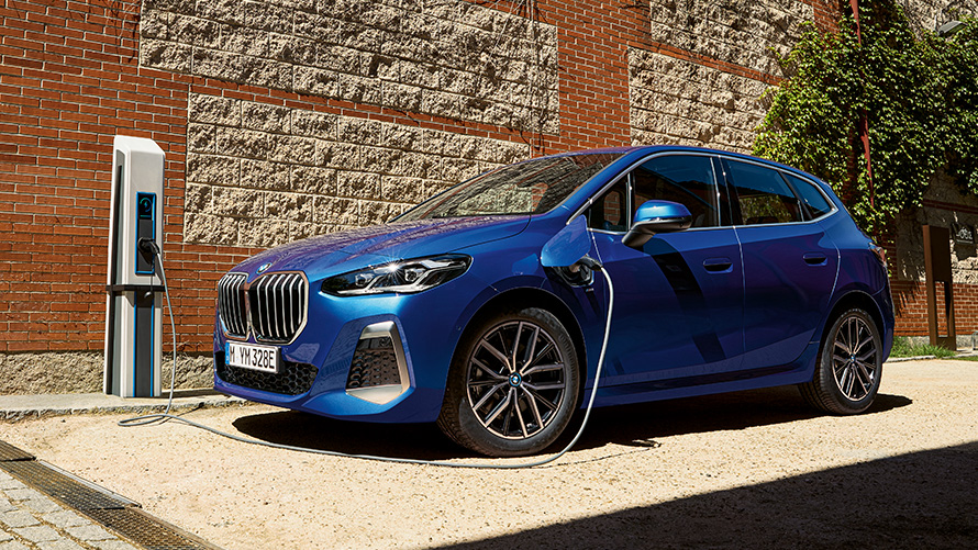 BMW 2 серії Active Tourer плагін-гібрид U06 2021 на зарядній станції BMW 2 серії Active Tourer 230e плагін-гібрид U06 2021 M у кольорі Portimao Blue металік, вид у три чверті збоку на зарядній станції