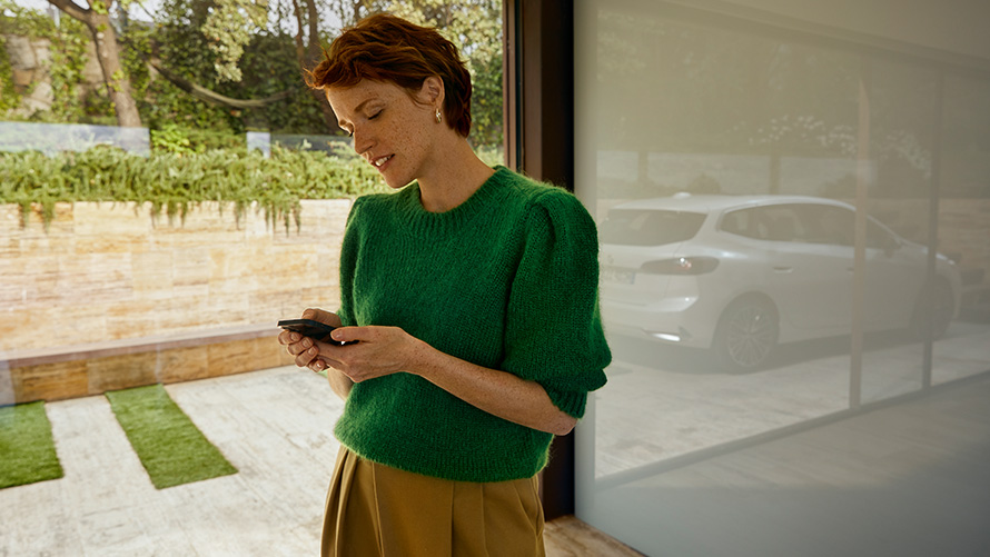 BMW Service Inclusive, жінка тримає смартфон Жінка тримає смартфон на BMW Service Inclusive