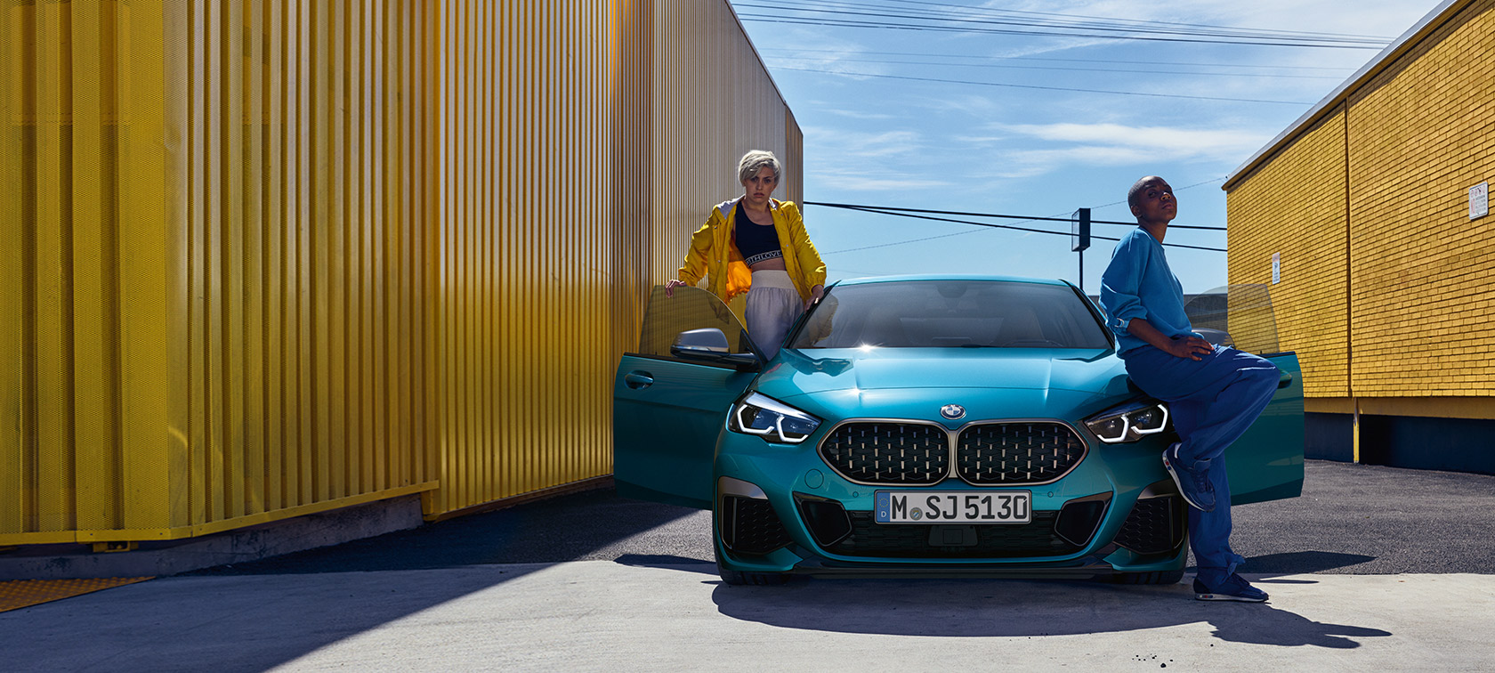 BMW 2 серії Gran Coupé F44, вид спереду BMW 2 серії Gran Coupé F44 у кольорі Snapper Rocks Blue, вид спереду з відкритими дверима та двома людьми біля автомобіля