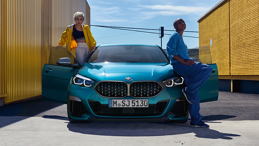BMW 2 серії Gran Coupé F44, вид спереду BMW 2 серії Gran Coupé F44 у кольорі Snapper Rocks Blue, вид спереду з відкритими дверима та двома людьми поруч з автомобілем