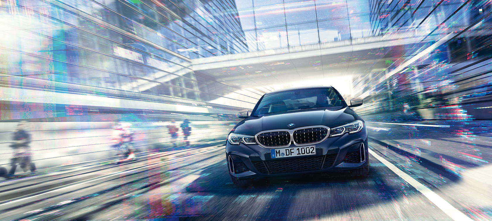 BMW 3 серії Седан, вид спереду BMW M340i xDrive. Вид спереду седана BMW M340i xDrive в русі між міськими скляними будівлями.