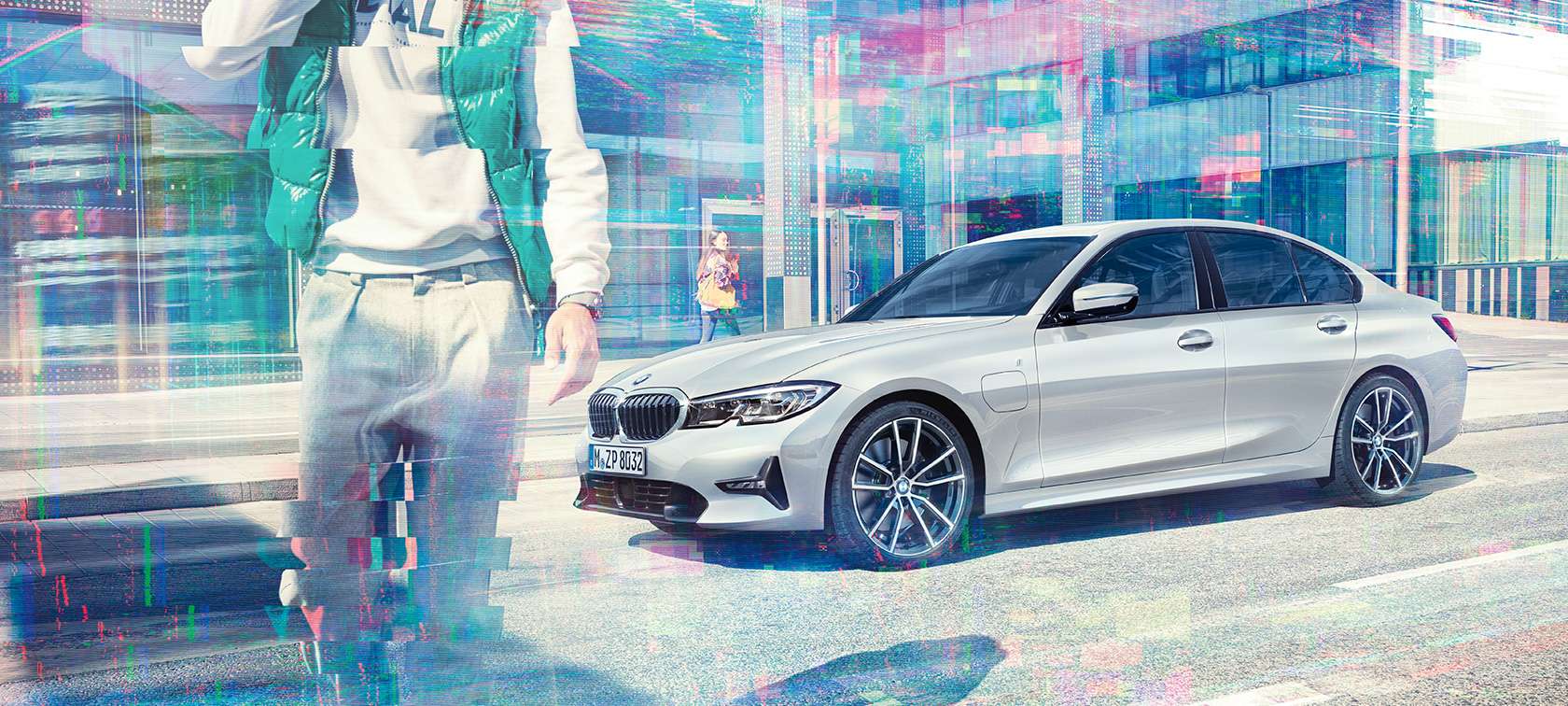 BMW 3 серії Седан, бічний знімок BMW 330е. Боковий знімок BMW 330e iPerformance Sedan перед міським скляним будівлею з пасажирами, що йдуть, три чверті.