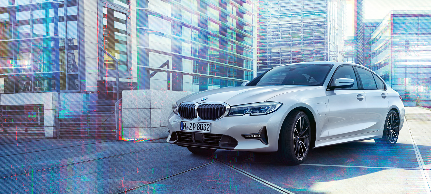 BMW 3 серії Седан 330e Передній знімок седана BMW 3 серії 330е на міському тлі з поворотом в три чверті.