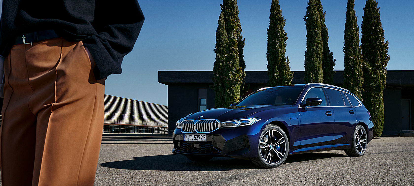BMW 3 серії Touring LCI G21 у кольорі Tansanit Blue II, вид спереду з поворотом у три чверті на фоні дерев