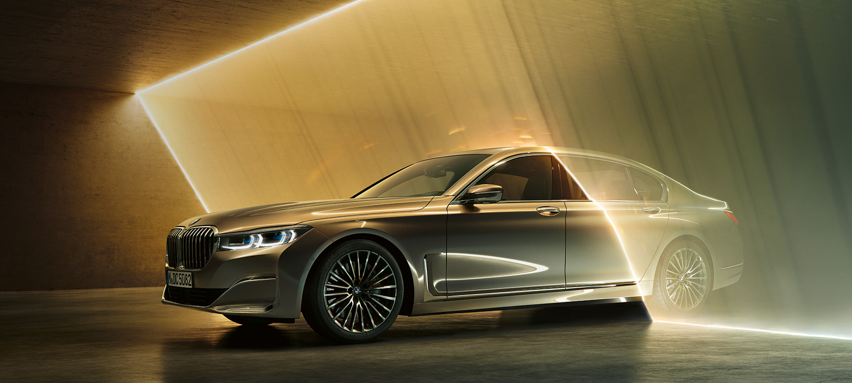 BMW 7 серії Седан: сірий BMW, вид спереду з поворотом в три чверті BMW 7 серії Седан: сірий BMW, вид спереду з поворотом в три чверті в оточенні потоків світла