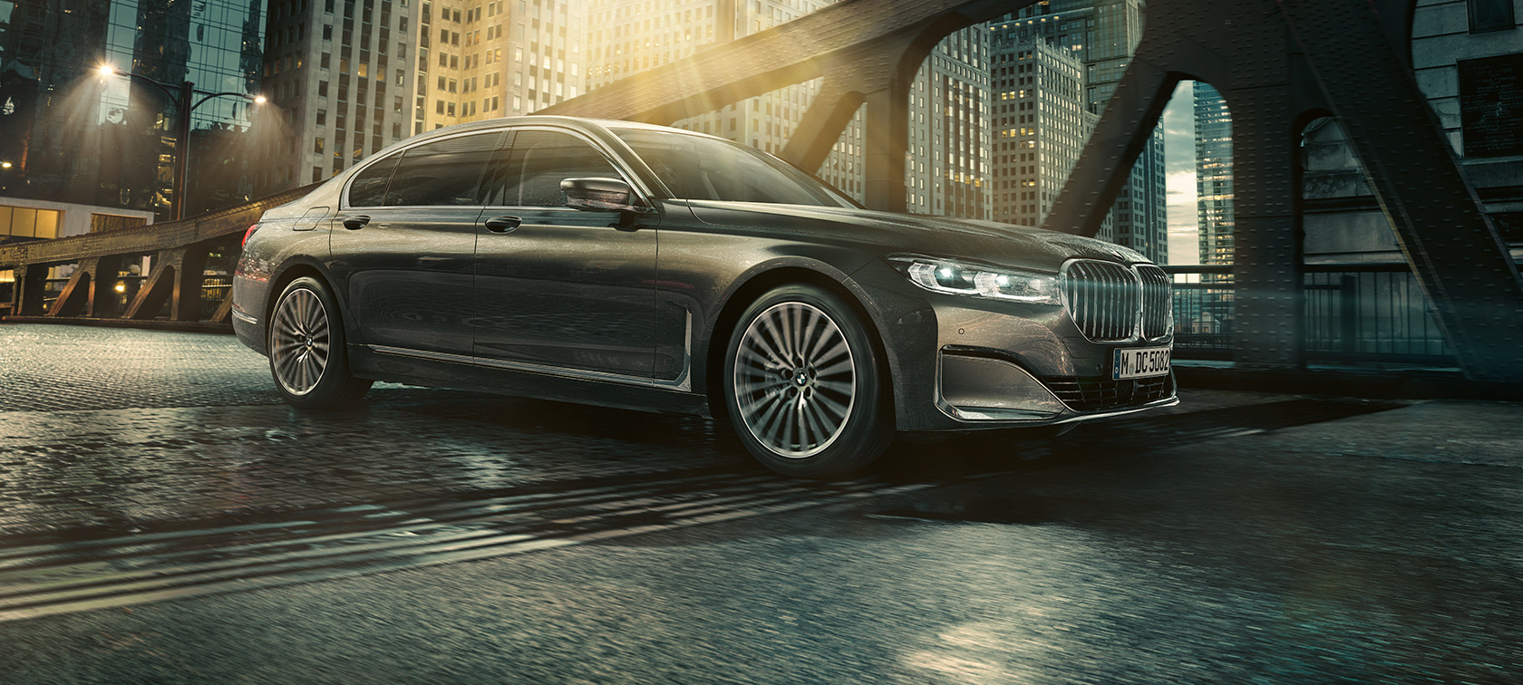 BMW 7 серии Седан G11 G12 2019, вид сбоку BMW 7 серии Седан G11 G12 2019 в цвете Bernina Grey Amber Effect, вид сбоку на три четверти в городе