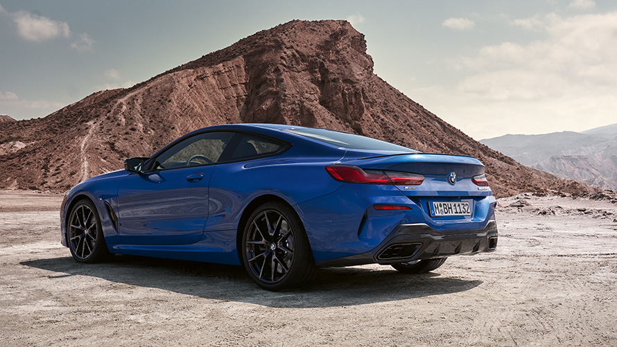 Вид збоку в три чверті на BMW 8 серії Coupe Пакет M Sport G15 LCI Facelift 2022 BMW 8 серії Coupe Пакет M Sport G15 LCI Facelift 2022 M у кольорі Portimao Blue metallic, вигляд збоку на фоні каміння
