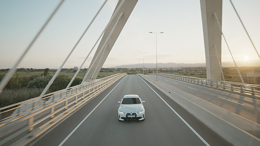 Вигляд спереду на три чверті на BMW i4 eDrive40 G26 2021 русі BMW i4 eDrive40 G26 2021 у кольорі Mineral White, вид спереду на три чверті в русі