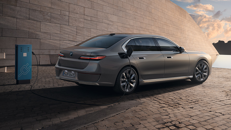 BMW i7 Седан G70 вид три чверті ззаду BMW i7 Седан G70 у кольорі BMW Individual Oxid grey metallic, вид три чверті ззаду на зарядній станції
