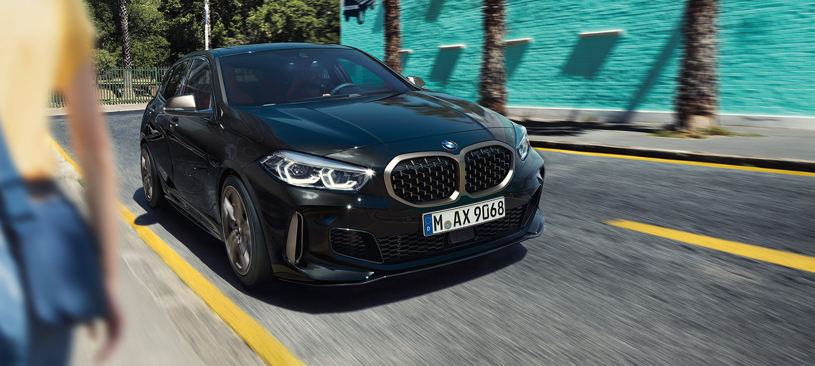 BMW M135i xDrive, вид спереду з поворотом в три чверті. BMW M135i xDrive в Black Sapphire металік, вид спереду за кермом з поворотом в три чверті.