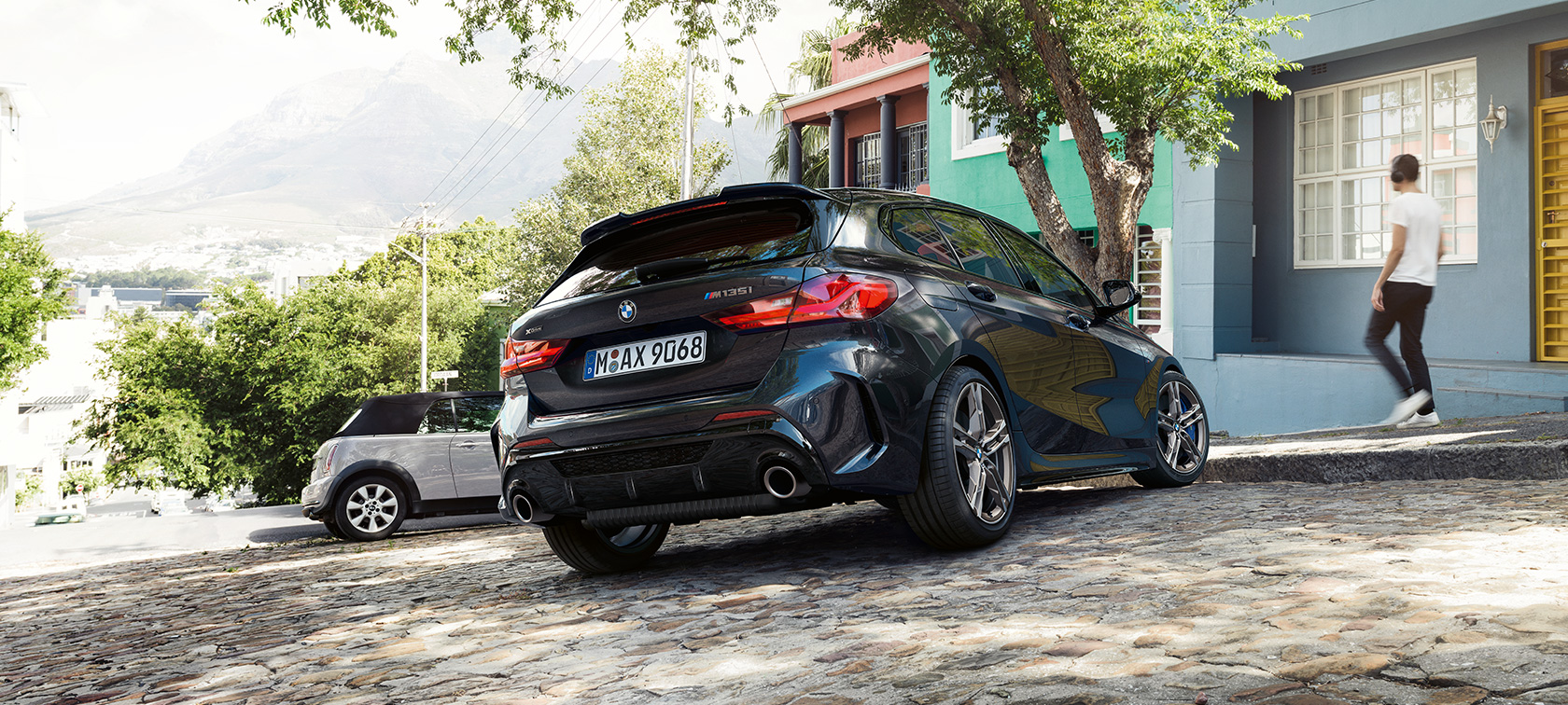 BMW M135i xDrive, вид ззаду з поворотом в три чверті. BMW M135i xDrive в Black Sapphire металік, вид ззаду з поворотом в три чверті, паркування перед житловим будинком.