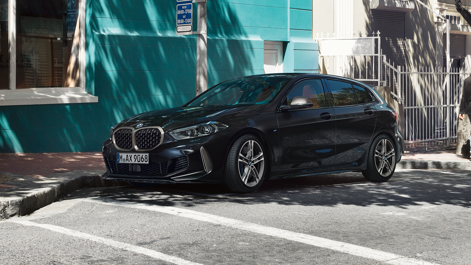 Новий BMW M135i xDrive, вид збоку з поворотом в три чверті. Новий BMW M135i xDrive в Black Sapphire металік, вид збоку з поворотом в три чверті, паркування.