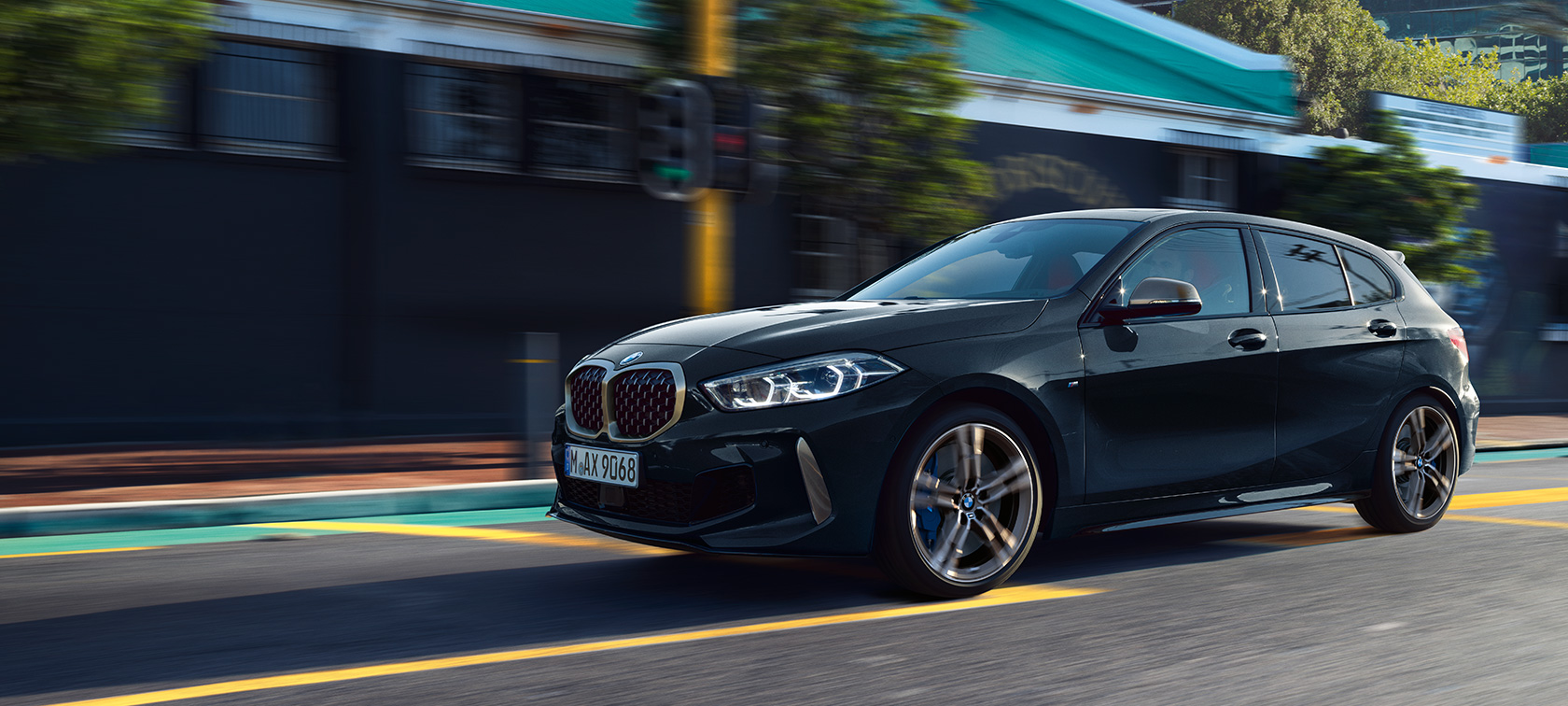 Новий BMW M135i xDrive в Black Sapphire металік, вид збоку за кермом з поворотом в три чверті.