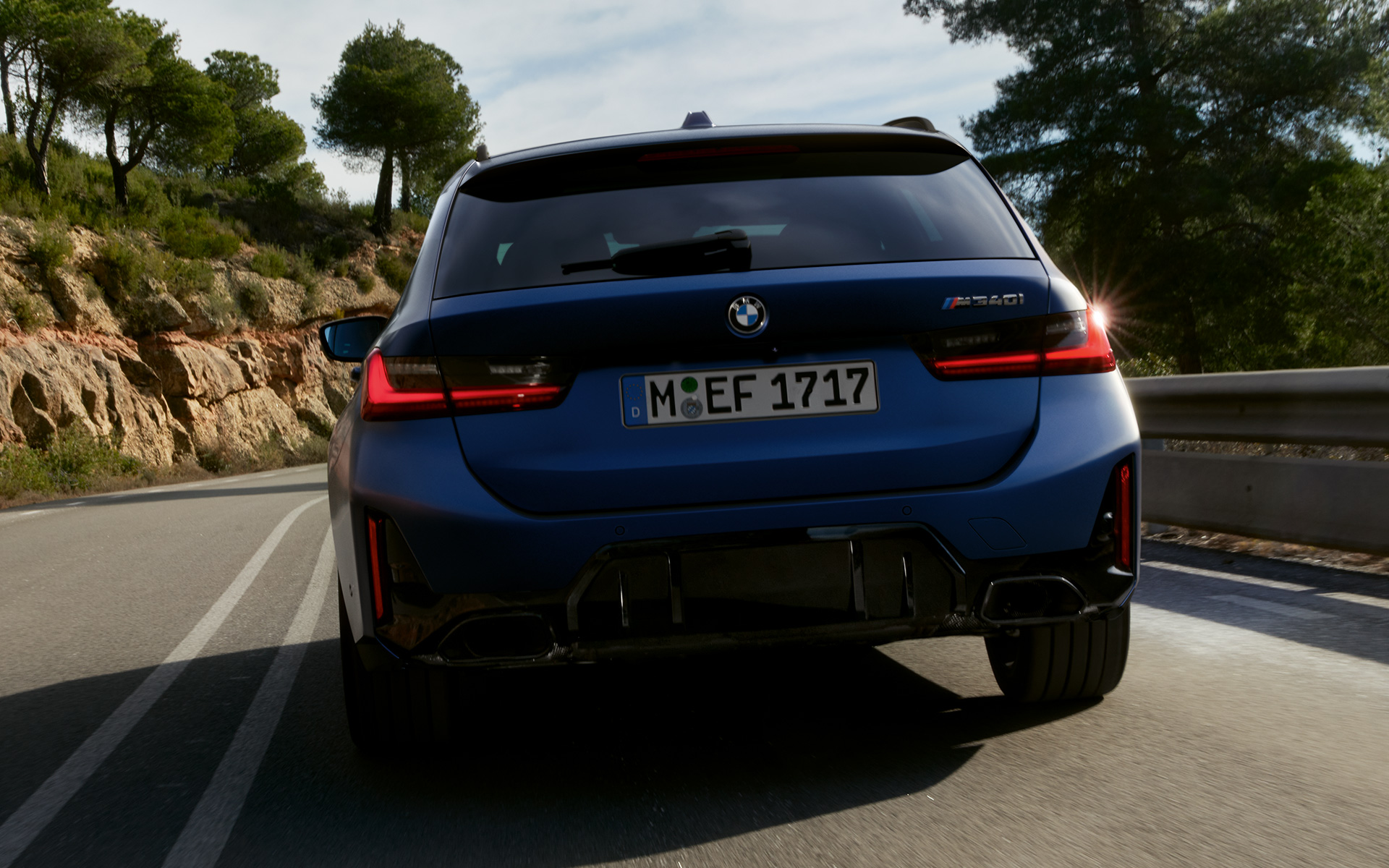 BMW M340i xDrive Touring G21, вид ззаду в русі на вулиці BMW M340i xDrive Touring G21 у кольорі Frozen Tanzanite Blue, вид ззаду в русі на вулиці