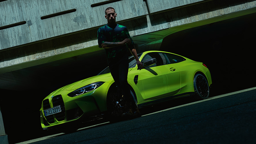 BMW M4 Coupé G82 2020 вид на передні три-чверті з моделлю попереду BMW M4 Coupé G82 2020 у кольорі Sao Paulo Yellow metallic вид на передні три четверті з моделлю