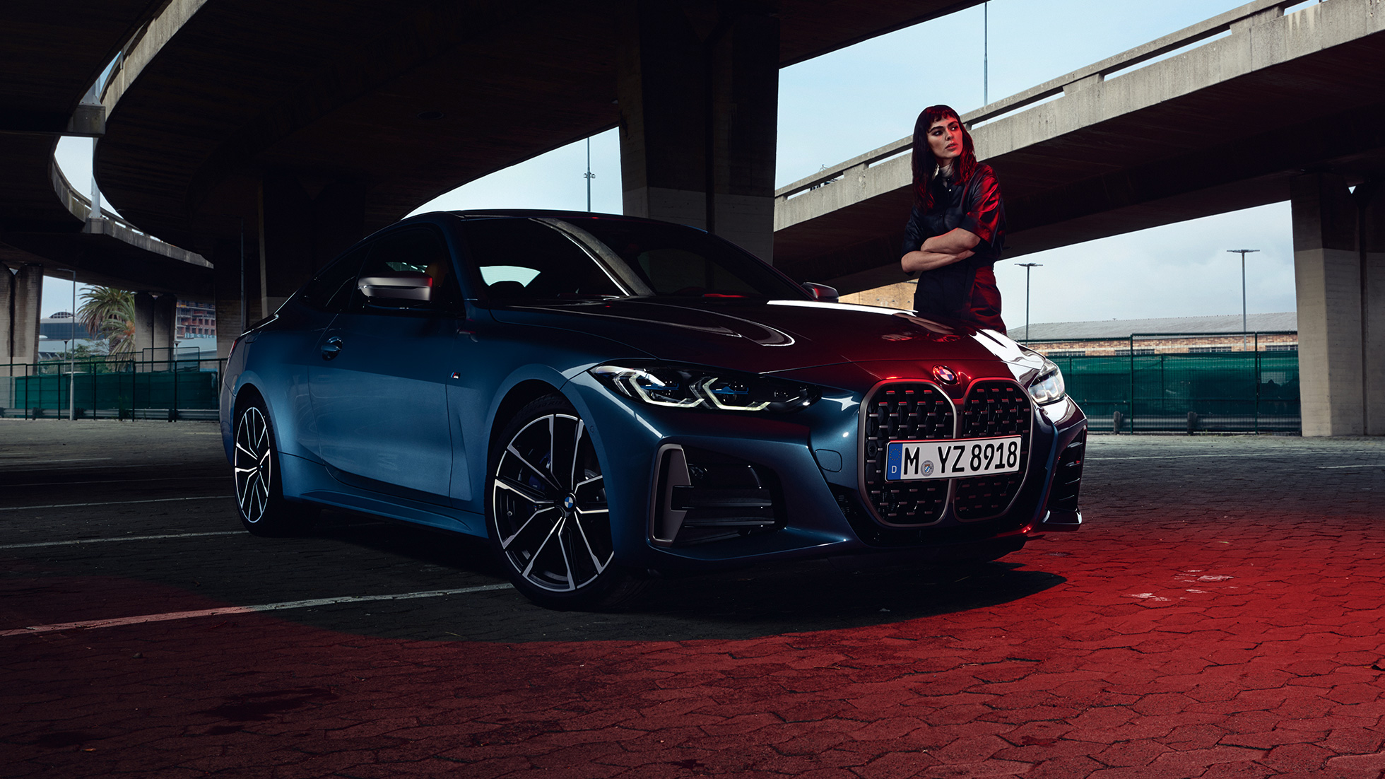 Мужчина стоит рядом с BMW M440i xDrive Coupe G22 (2020), вид сбоку с поворотом в три четверти Модель рядом с BMW M440i xDrive Coupe G22 (2020), Синий Арктик Рэйс металлик, вид сбоку с поворотом в три четверти