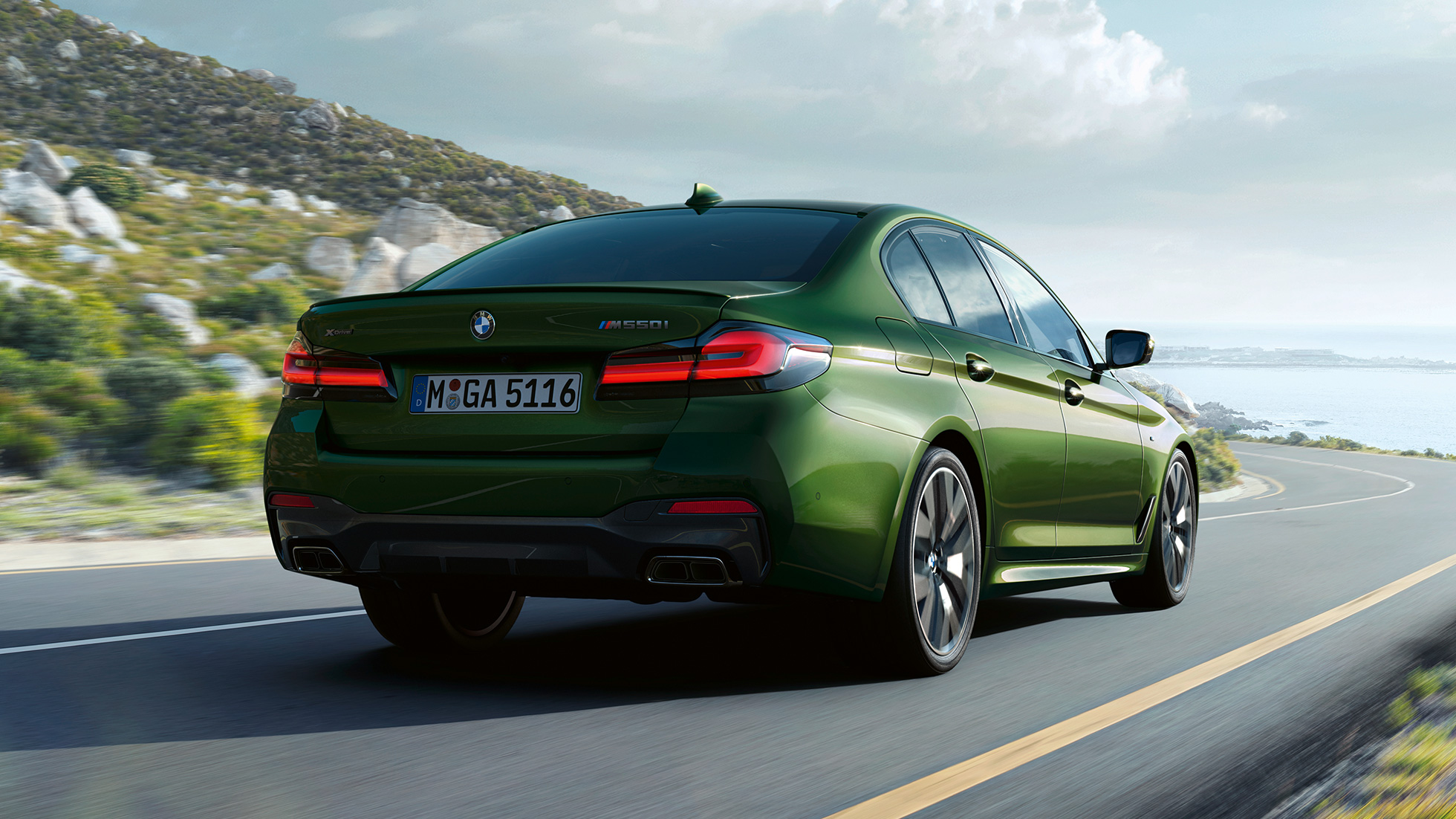 BMW M550i xDrive Седан G30 LCI 2020 вид ззаду BMW M550i xDrive Седан G30 LCI 2020 кольору BMW Individual Verde Ermes Metallic вид ззаду під час руху на гоночній трасі