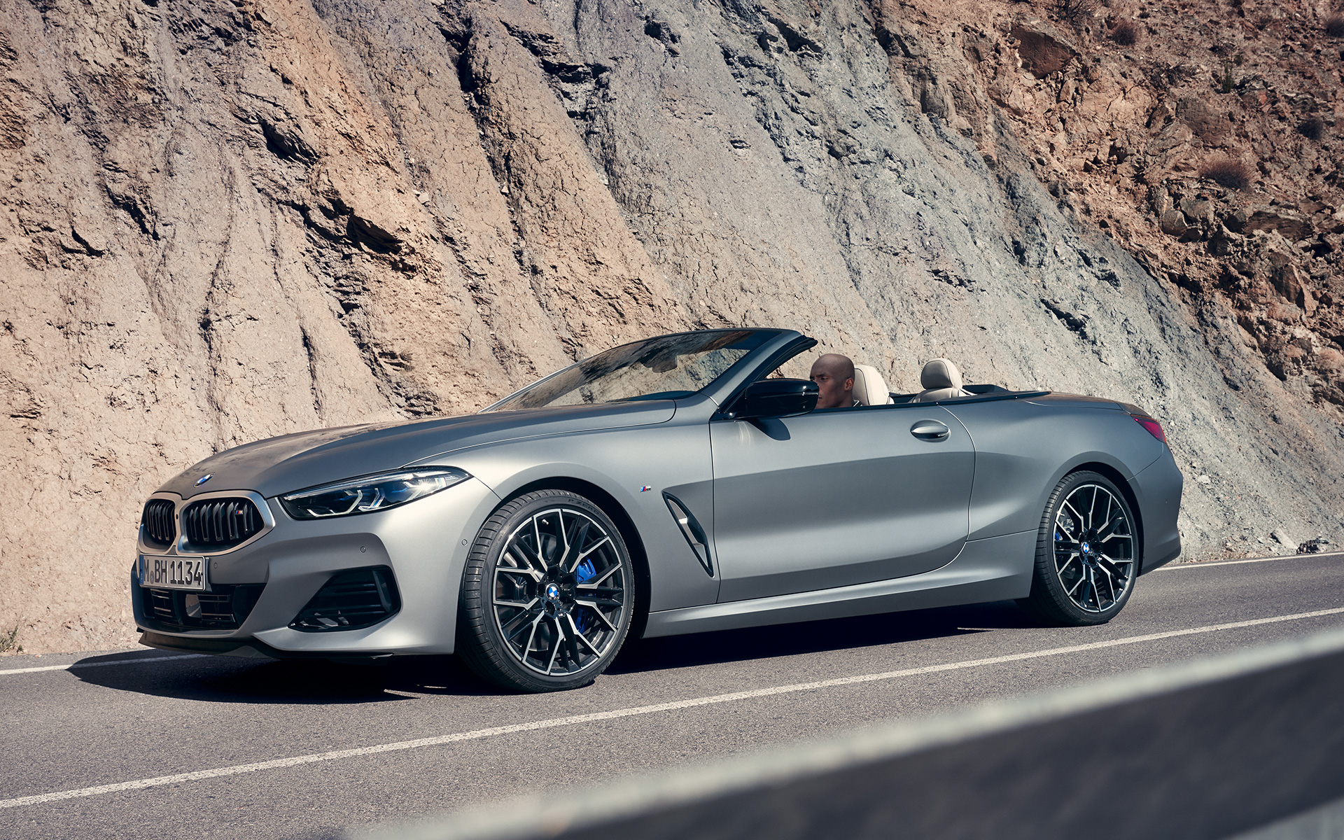 Вид спереду на три чверті BMW M850i xDrive Cabrio G14 LCI Facelift 2022 BMW М850і xDrive Cabrio G14 LCI Facelift 2022 у кольорі BMW Individual Frozen Pure Grey metallic, вид спереду на три чверті під час їзди
