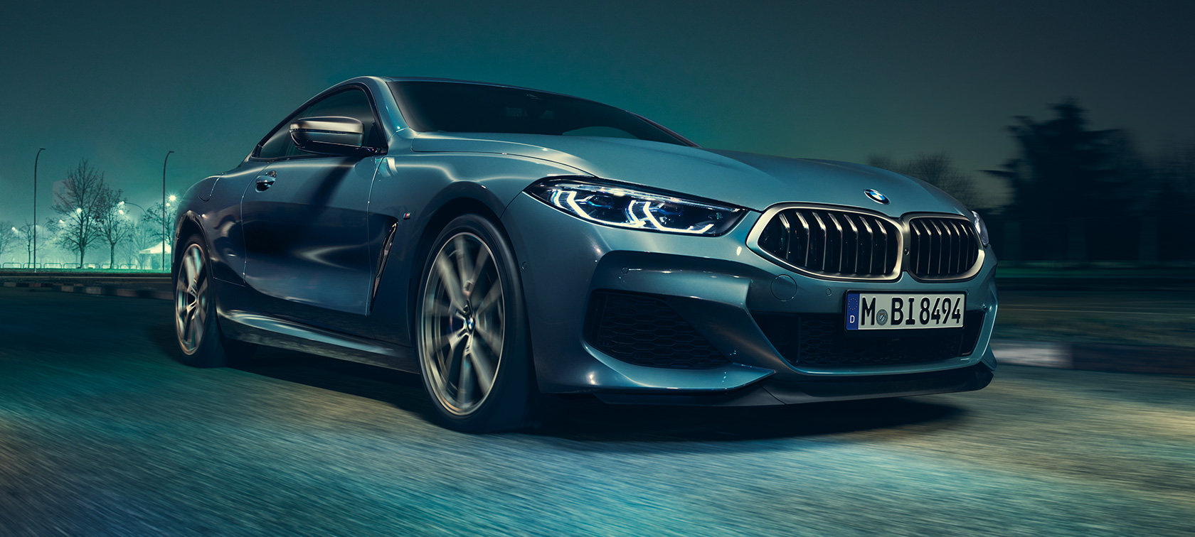 BMW M850i xDrive Coupé, вид спереду з поворотом в три чверті. BMW M850i xDrive Coupé в Barcelona Blue металік за кермом, вид спереду з поворотом в три чверті.