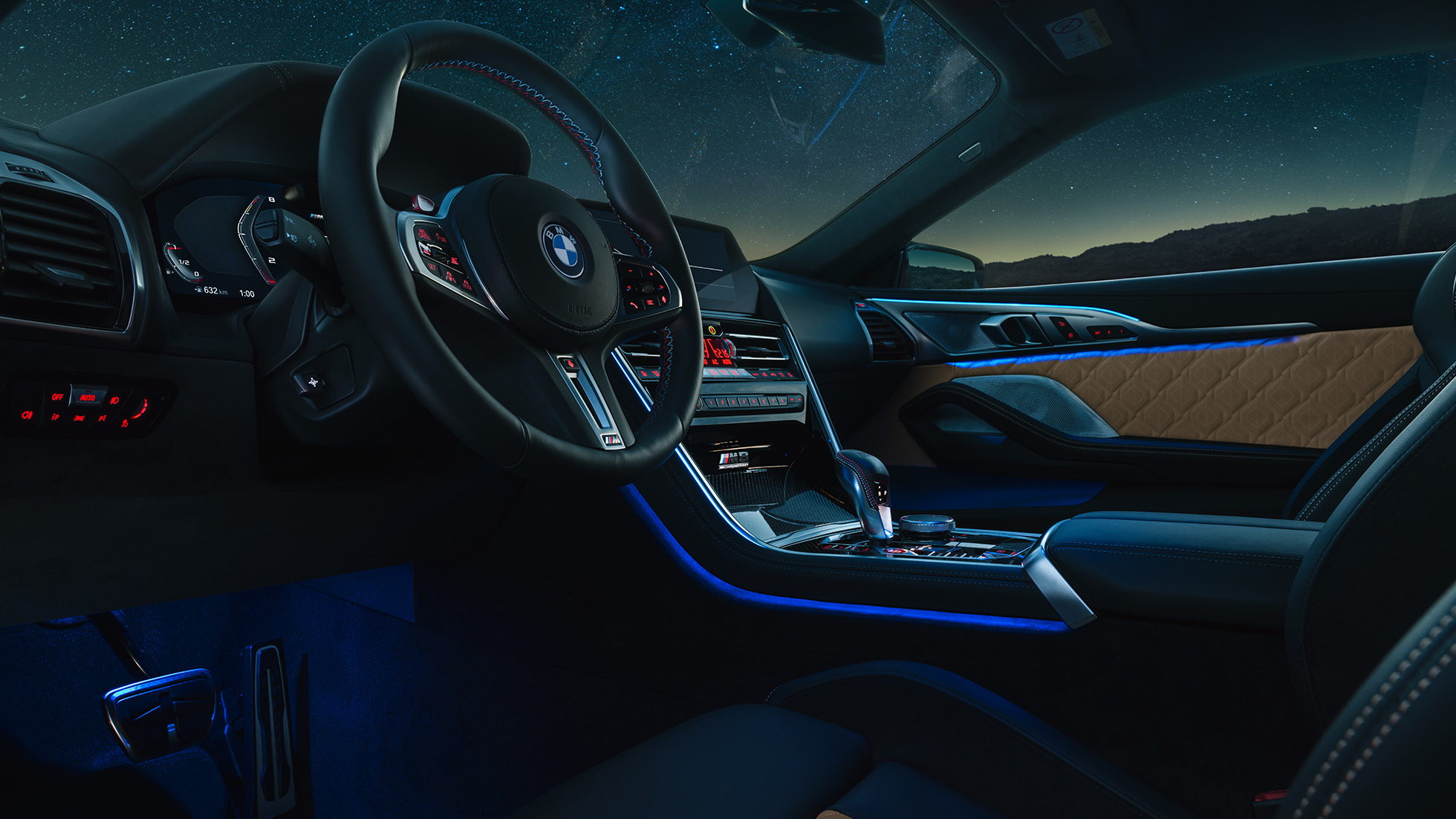 BMW M8 Competition Coupé, кабіна. BMW M8 Competition Coupé, кабіна вночі з шкіряним рульовим колесом M і синім фоновим освітленням.