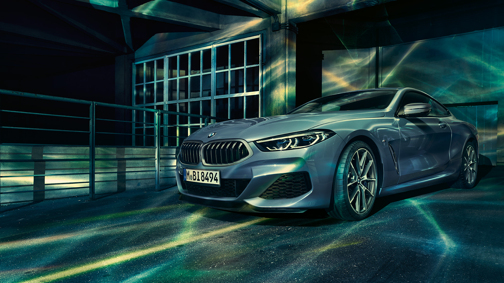 BMW M850i xDrive Coupé, вид спереду з поворотом в три чверті. BMW M850i xDrive Coupé в Barcelona Blue металік, вид спереду з поворотом в три чверті, перед будівлею.