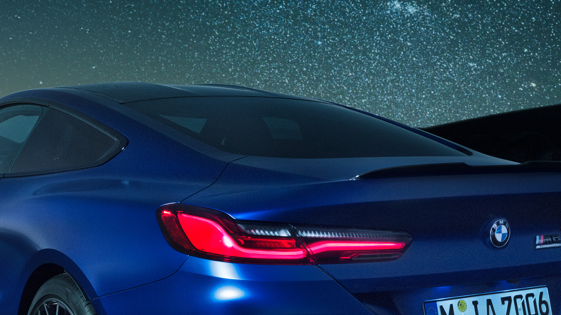 Задній спойлер М BMW M8 Competition Coupé в Marina Bay Blue металік, нічна зйомка плечової частини з заднім спойлером M в карбоні.