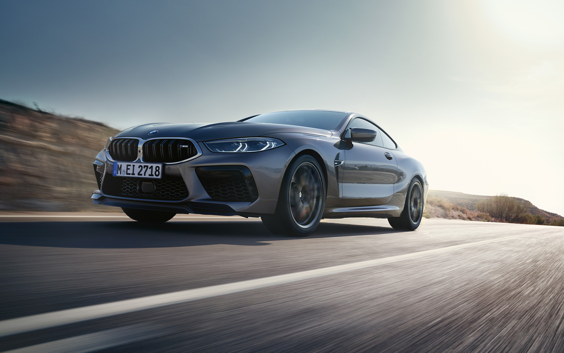 Вид спереду на три чверті BMW M8 Coupe F92 LCI Facelift 2022 під час їзди на шосе BMW M8 Сoupe F92 LCI Facelift 2022 кольору Skyscraper grey metallic, вид спереду на три чверті знизу під час їзди
