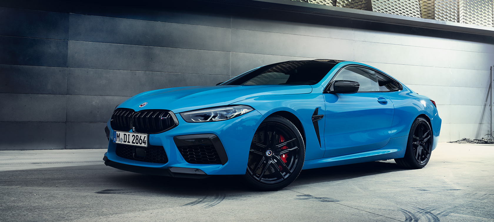 BMW M8 Coupe F92 LCI Facelift 2022 у кольорі BMW Individual Daytona Beach Blue, вид збоку на три чверті на фоні стіни