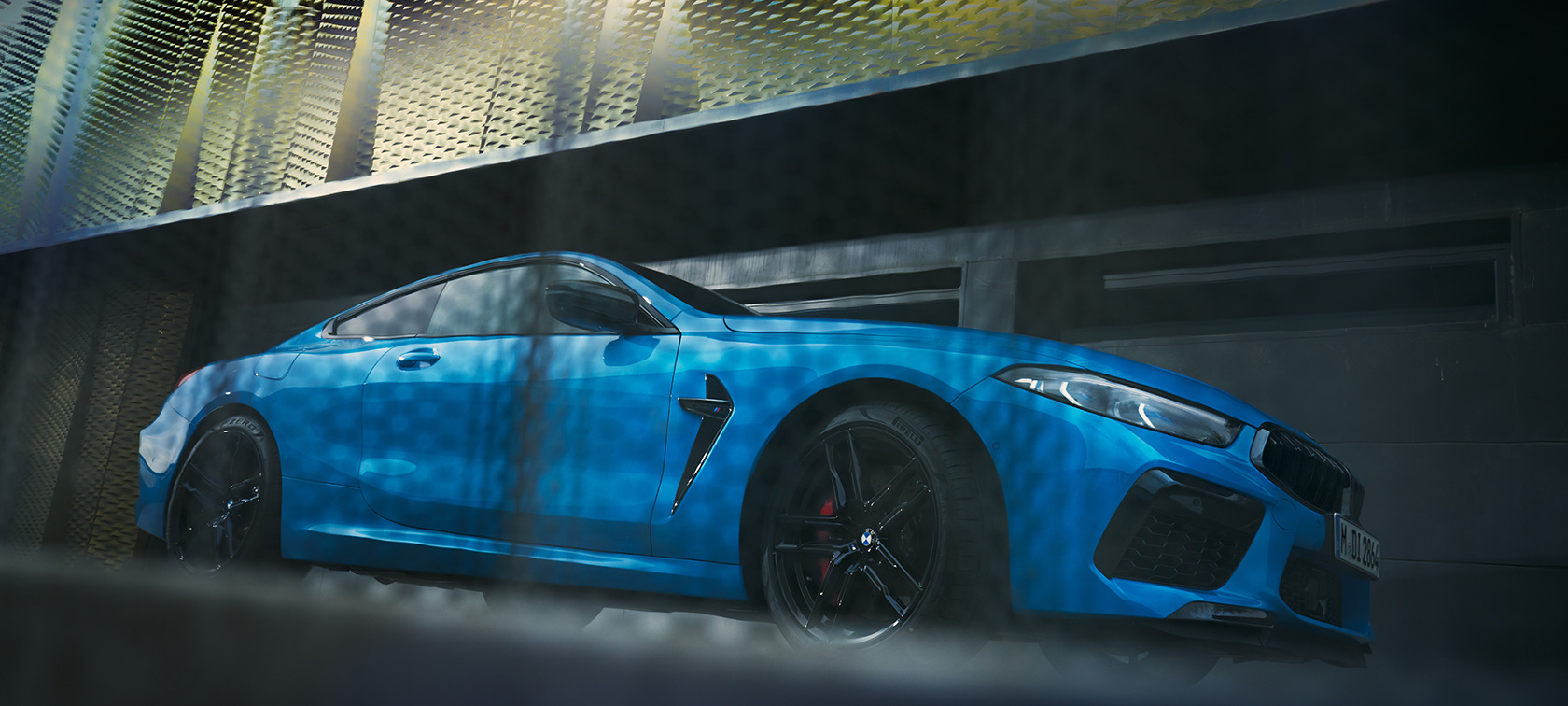 BMW M8 Competition Coupe F92 LCI Facelift 2022 вид збоку з нижнього ракурсу BMW M8 Coupe F92 LCI Facelift 2022 у кольорі BMW Individual Daytona Beach Blue, вид збоку на фоні стіни з нижнього ракурсу