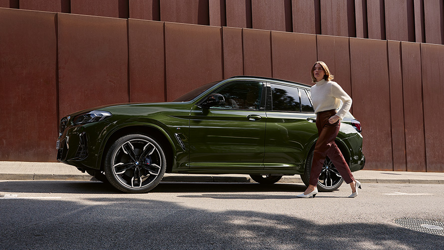 BMW X3 M G01 LCI Facelift 2021 в кольорі Malachite Green металік, вид збоку з жінкою моделлю