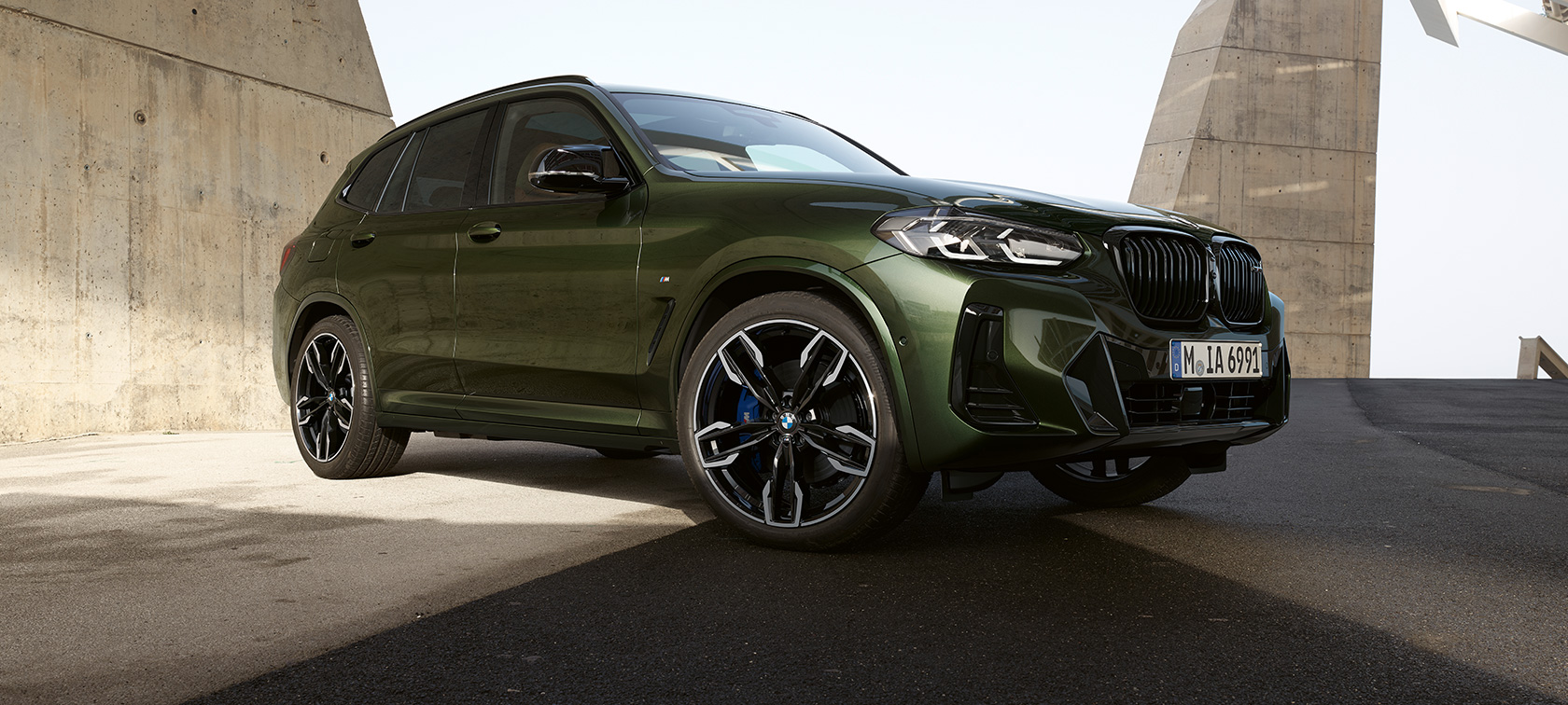BMW X3 M40i G01 LCI 2021 Facelift, вид спереду в три чверті на місці BMW X3 M F97 LCI Facelift 2021 в кольорі Malachite Green металік, вид спереду в три чверті на місці